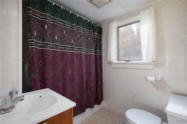 bathroom featuring vanity, toilet, and tile walls