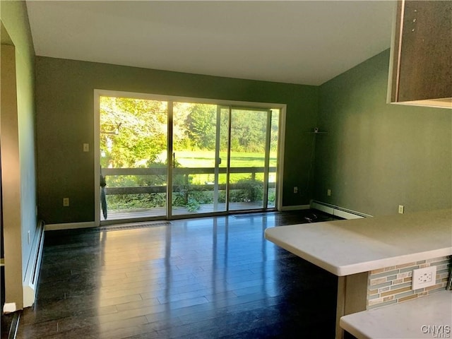 unfurnished living room featuring a baseboard heating unit, a healthy amount of sunlight, and hardwood / wood-style floors