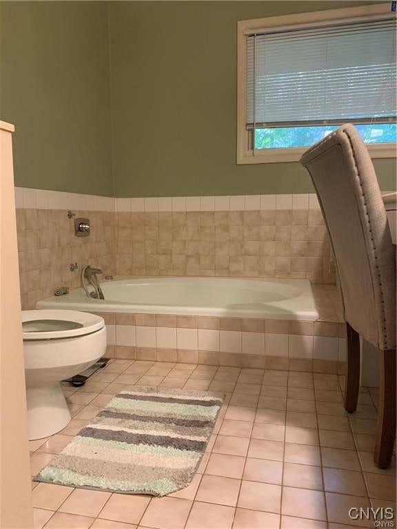 bathroom with toilet, tiled bath, and tile patterned flooring