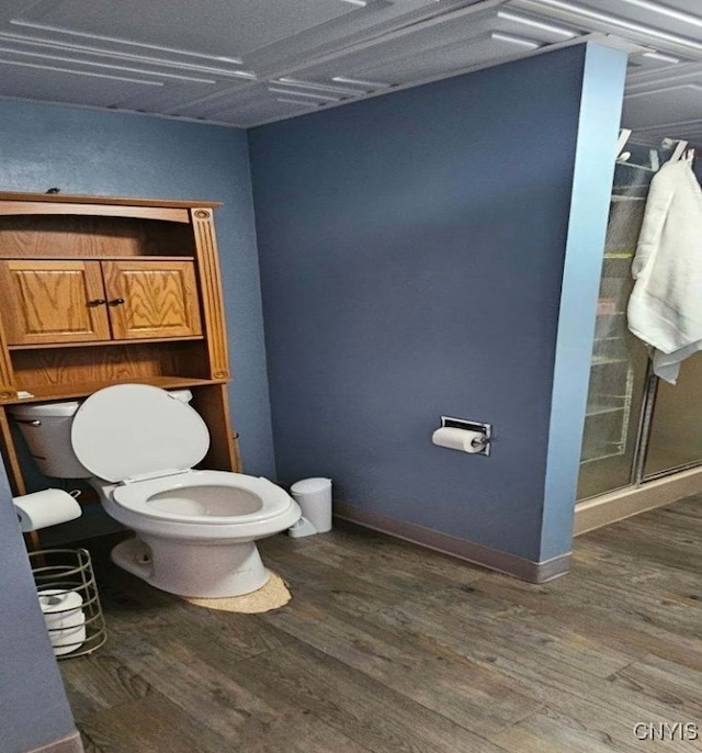 bathroom with hardwood / wood-style floors, a shower with shower door, and toilet