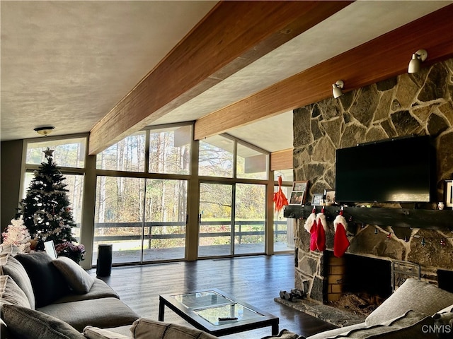 living room featuring beam ceiling, a fireplace, wood-type flooring, and floor to ceiling windows