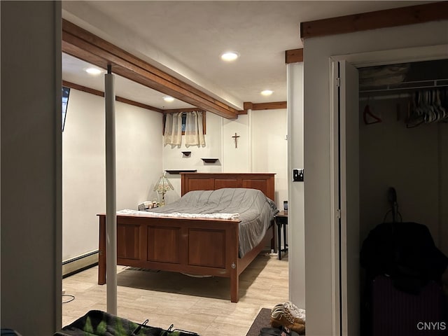 bedroom featuring baseboard heating, light wood-type flooring, and a closet