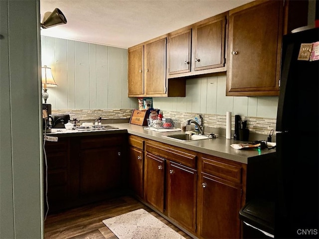 kitchen featuring decorative backsplash, sink, dark wood-type flooring, and black fridge