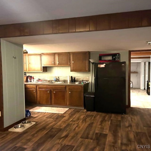 kitchen featuring sink, tasteful backsplash, black appliances, and dark hardwood / wood-style flooring