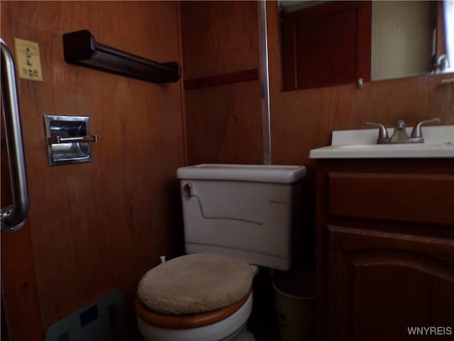 bathroom featuring vanity, wooden walls, and toilet