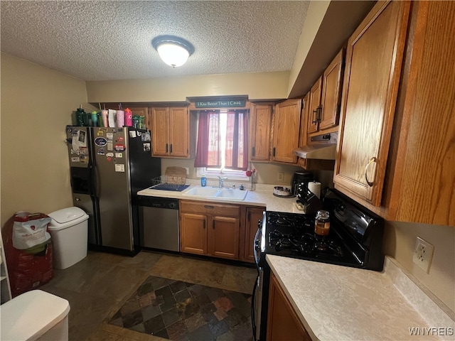 kitchen with a textured ceiling, appliances with stainless steel finishes, and sink