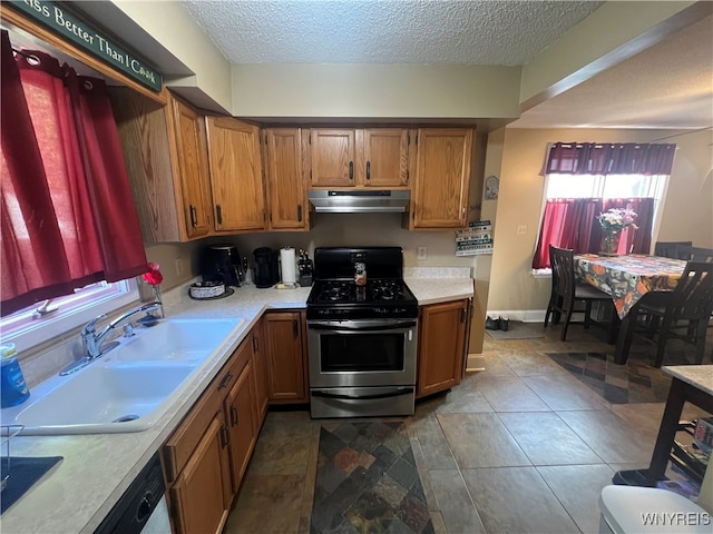 kitchen with dishwashing machine, a textured ceiling, stainless steel range with gas cooktop, and sink