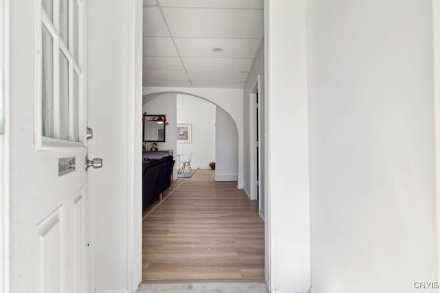 hallway with a paneled ceiling and light hardwood / wood-style floors