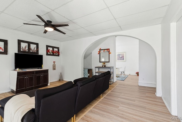 living room with a paneled ceiling, light wood-type flooring, and ceiling fan