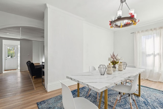 dining room with a notable chandelier, ornamental molding, and light hardwood / wood-style flooring