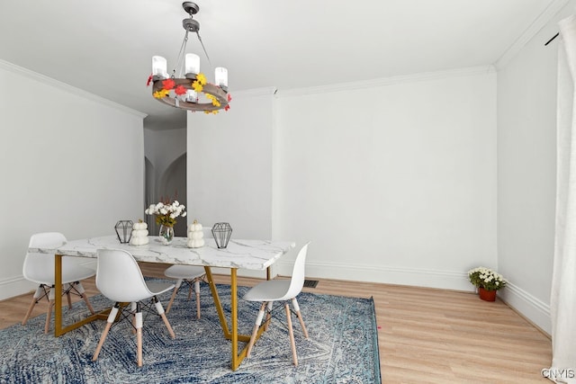 dining area with crown molding, wood-type flooring, and a chandelier