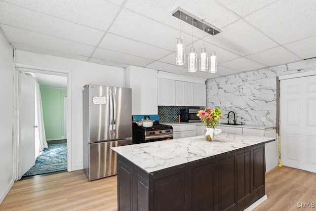 kitchen featuring appliances with stainless steel finishes, light hardwood / wood-style flooring, decorative light fixtures, and white cabinetry