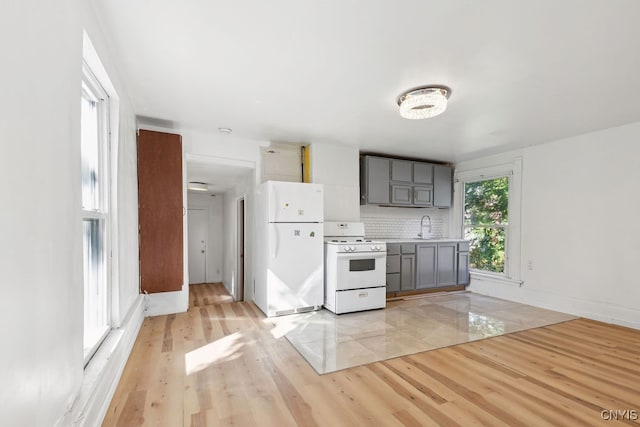 kitchen featuring decorative backsplash, gray cabinetry, sink, light wood-type flooring, and white appliances