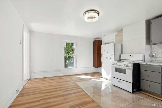 kitchen with decorative backsplash, light hardwood / wood-style flooring, gray cabinetry, and white appliances