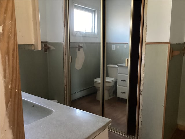 bathroom with toilet, hardwood / wood-style flooring, vanity, and a shower with door