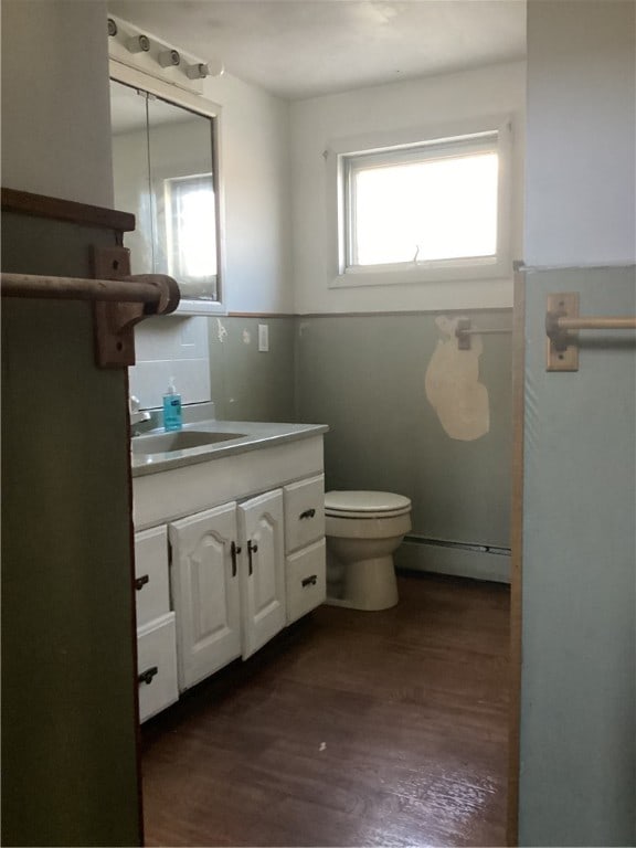 bathroom with vanity, a baseboard heating unit, hardwood / wood-style flooring, and toilet