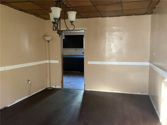 empty room with a drop ceiling and dark hardwood / wood-style floors