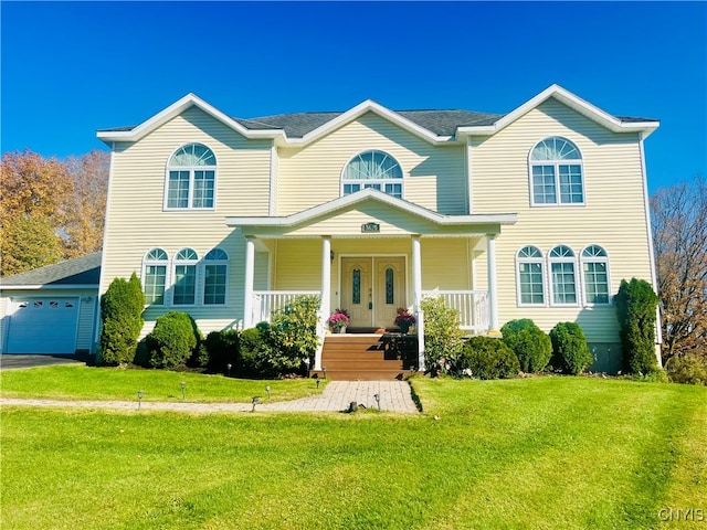 view of front of property featuring a porch, a front lawn, and a garage