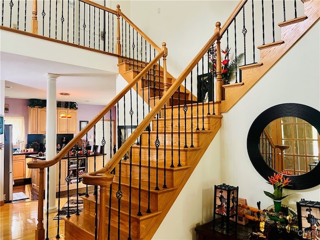 staircase with ornate columns and hardwood / wood-style floors