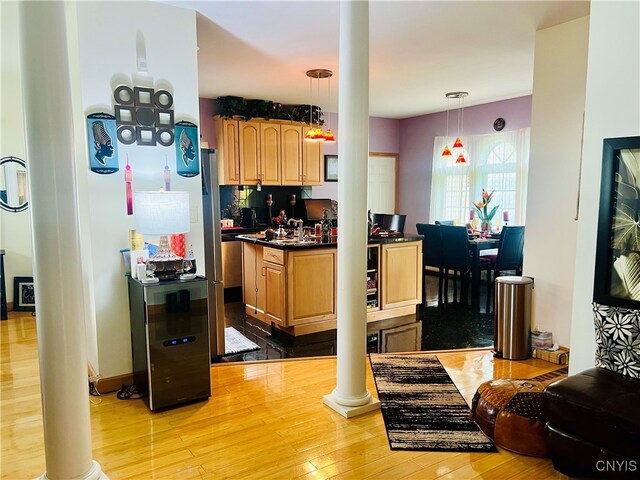 kitchen featuring hanging light fixtures, ornate columns, and light hardwood / wood-style floors