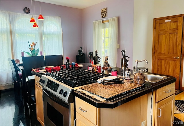 kitchen featuring light brown cabinets, hanging light fixtures, a kitchen island, stainless steel range with gas stovetop, and sink