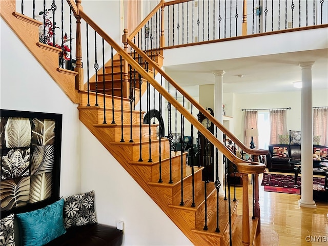 stairs with ornate columns and wood-type flooring