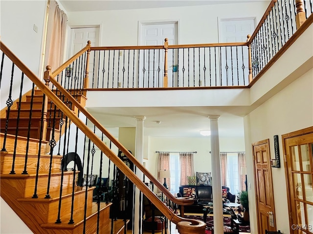 stairs featuring a towering ceiling and decorative columns