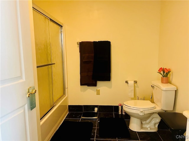 bathroom featuring toilet, tile patterned flooring, and bath / shower combo with glass door