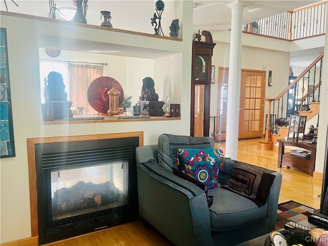 interior space with a multi sided fireplace, wood-type flooring, and ornate columns