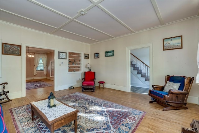 living room featuring baseboards, stairway, coffered ceiling, and wood finished floors