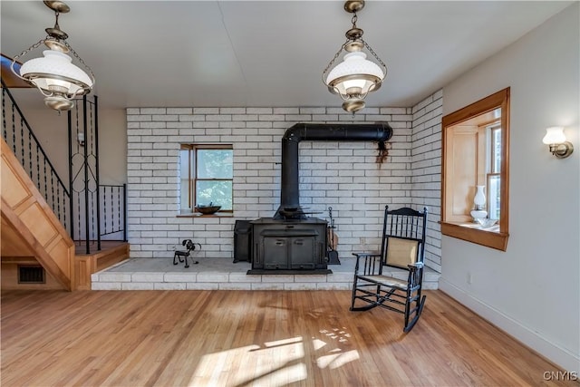 sitting room with baseboards, visible vents, stairway, wood finished floors, and a wood stove