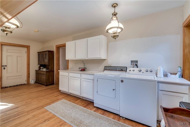 laundry area with light wood-style floors, cabinet space, and independent washer and dryer