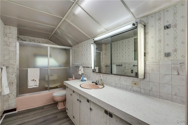 bathroom featuring shower / bath combination with glass door, vanity, toilet, and wallpapered walls