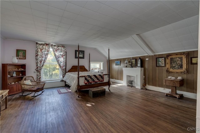 bedroom with a fireplace, vaulted ceiling, wood walls, and wood finished floors