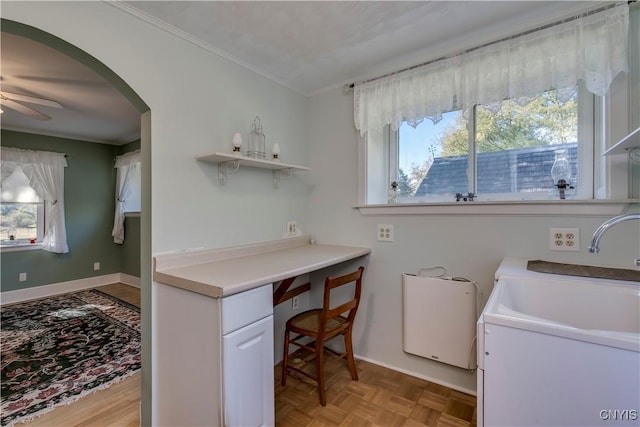 clothes washing area with arched walkways, ornamental molding, a sink, ceiling fan, and laundry area