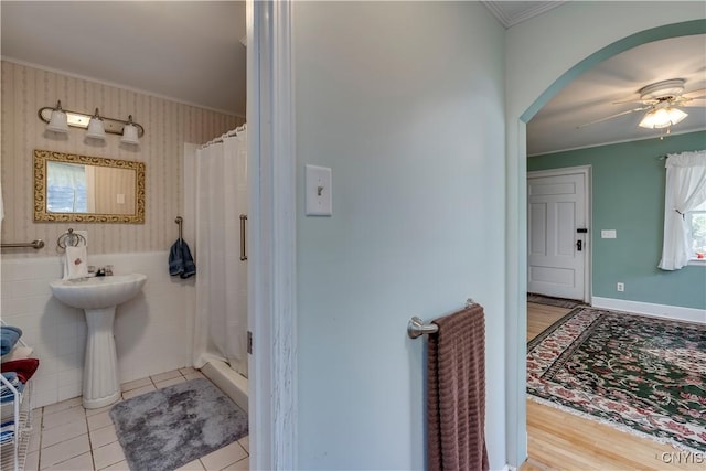 bathroom with wallpapered walls, ornamental molding, and a stall shower