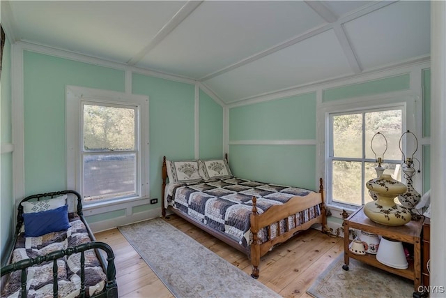 bedroom with ornamental molding, vaulted ceiling, and hardwood / wood-style flooring