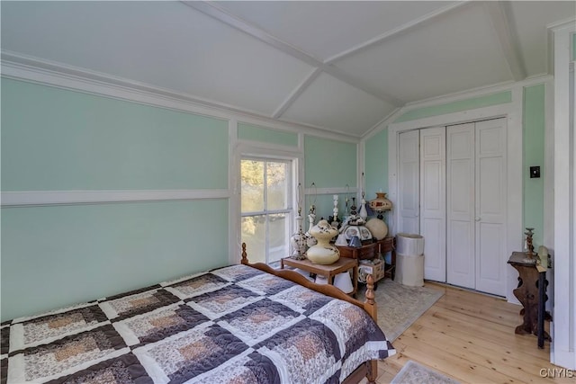 bedroom with a closet, ornamental molding, and wood finished floors