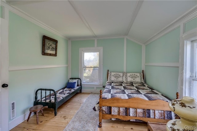 bedroom featuring vaulted ceiling, wood-type flooring, visible vents, and crown molding