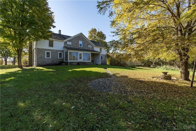 traditional-style house featuring stone siding and a front lawn