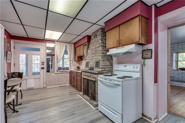 kitchen with electric stove, light wood-type flooring, a wealth of natural light, and under cabinet range hood