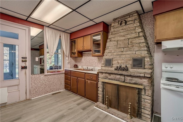 kitchen with white range with electric stovetop, visible vents, light wood-type flooring, under cabinet range hood, and a sink