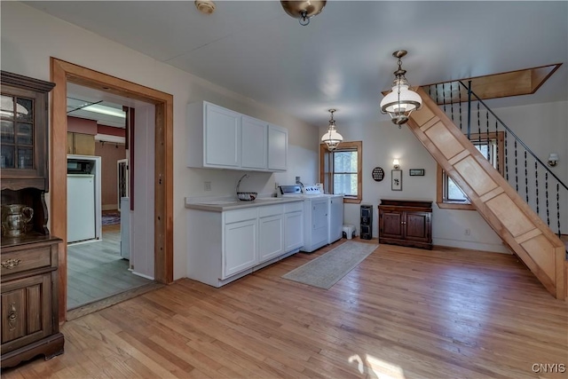 kitchen with light wood-style floors, white cabinetry, washer / clothes dryer, and pendant lighting