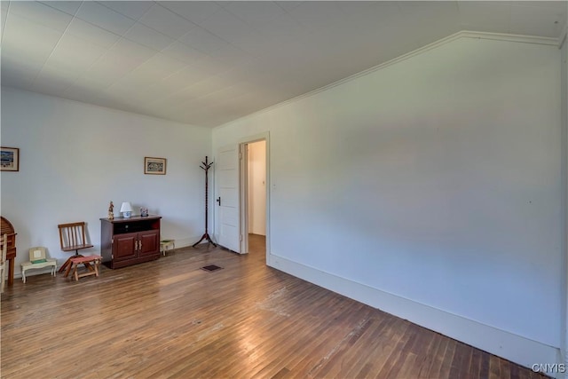 unfurnished room featuring lofted ceiling, baseboards, visible vents, and wood finished floors