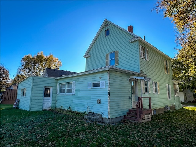 rear view of property featuring a lawn