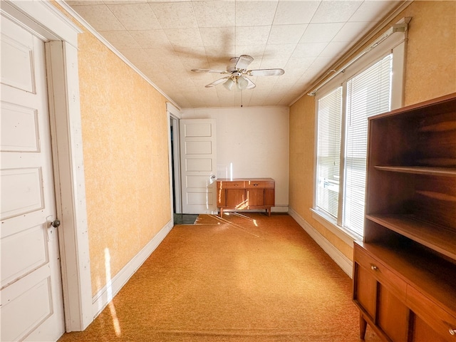 carpeted empty room featuring crown molding and ceiling fan