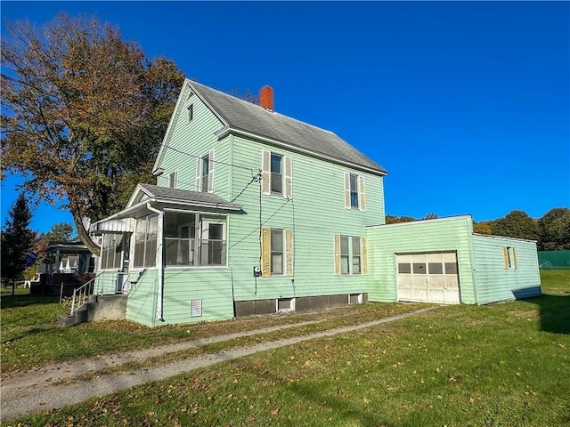 rear view of house featuring a lawn and a sunroom