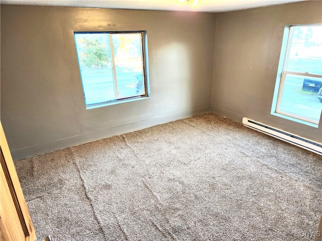 spare room with a baseboard heating unit, carpet flooring, and a wealth of natural light