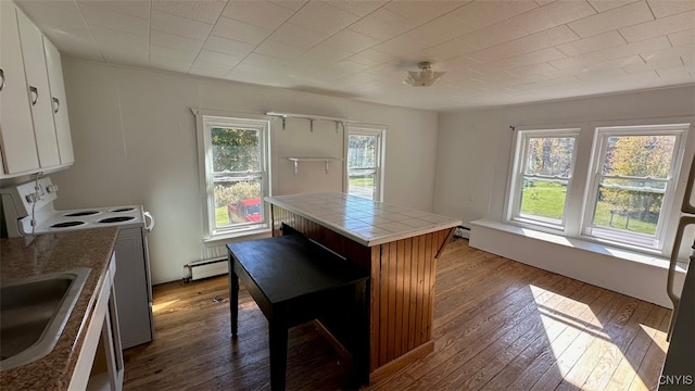 kitchen with light hardwood / wood-style flooring, white cabinets, baseboard heating, and tile counters