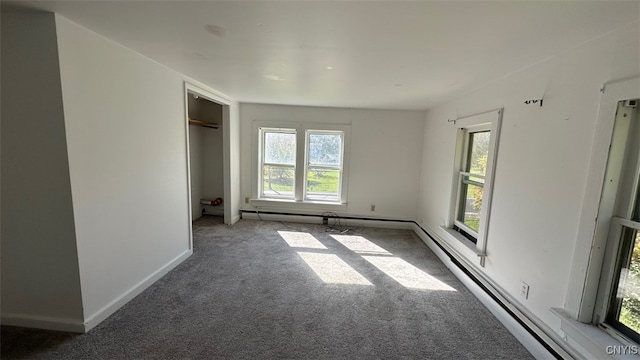 unfurnished bedroom featuring baseboard heating and dark colored carpet